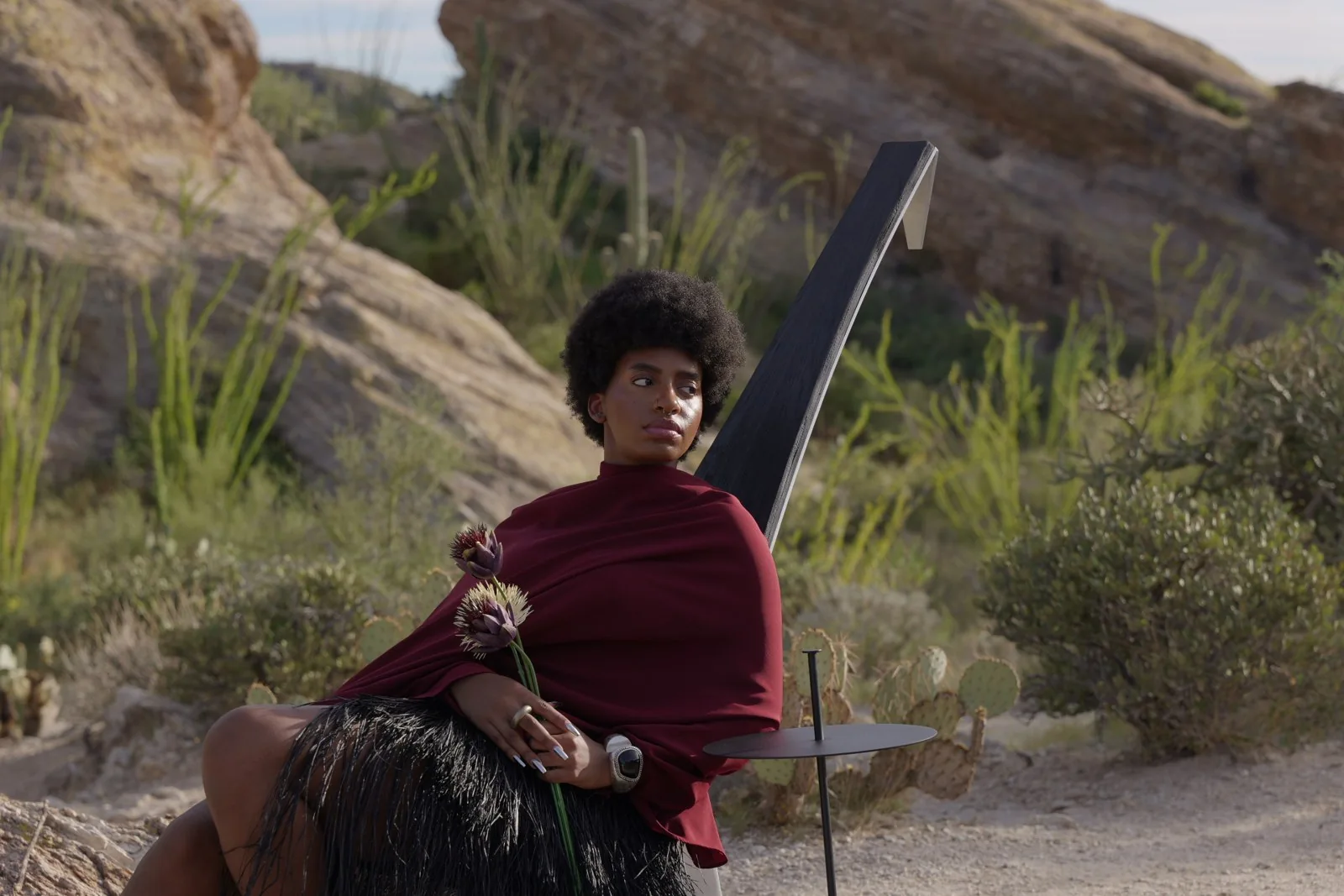 Model seated in a DÂ-NIYI chair in the desert